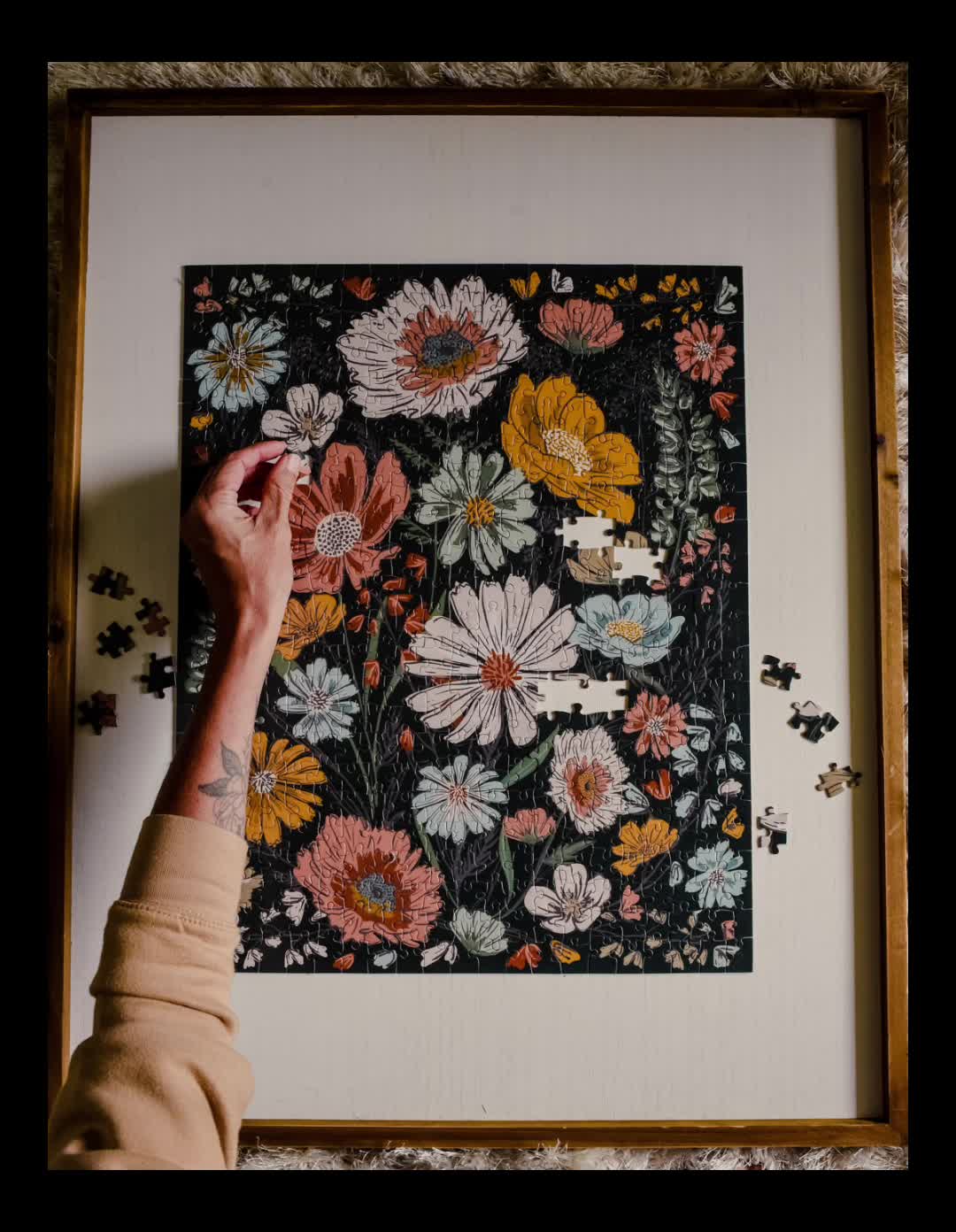 This may contain: a person is holding up a piece of art that has flowers on it in front of a white frame