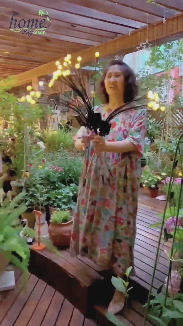 This may contain: a woman standing on top of a wooden deck next to potted plants and flowers