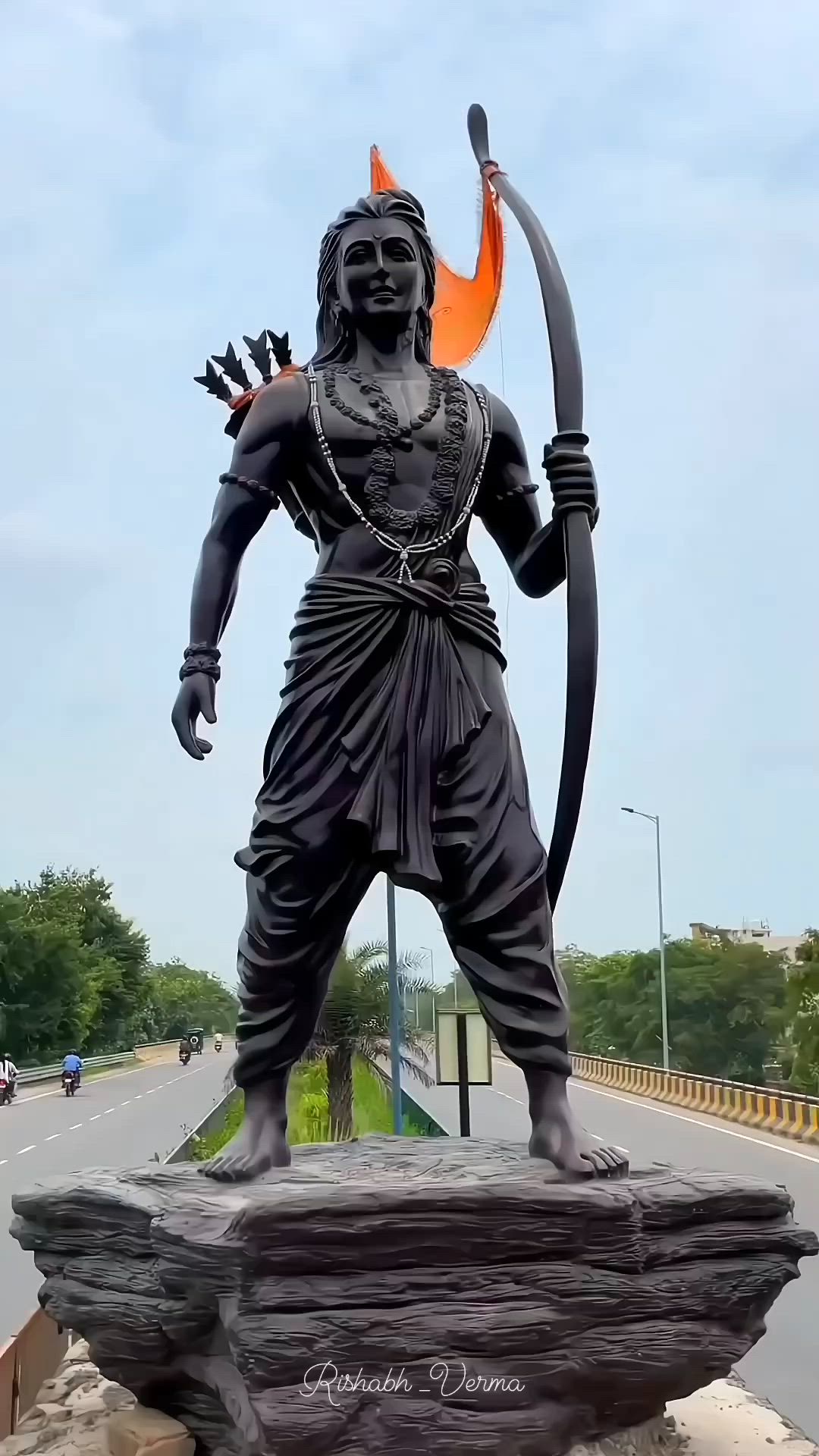 This may contain: a statue of a man holding a bow and an arrow in front of a highway