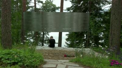 A person sitting underneath the memorial to Breivik's victims