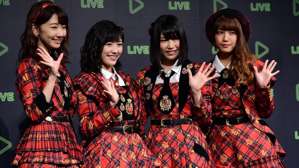 Japan's girl pop group AKB48 members pose for photographs as Japanese social networking service company Line announces the company's live streaming service in Tokyo on 10 December 2015