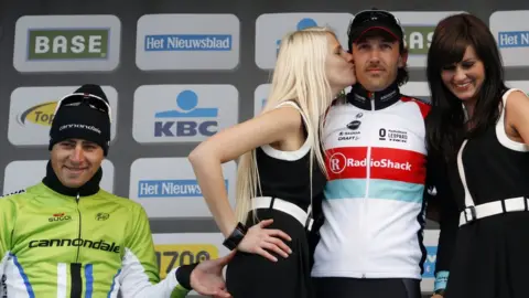 Reuters Peter Sagan pinching a podium girl's bottom on the winner's podium, with Fabio Cancellara and two podium girls in the picture