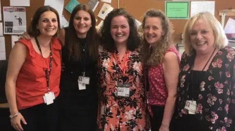 Heidi Curry Five women huddled together in a classroom all smiling - (left to right) teachers Sam Kerr and Heidi Curry, with former pupil Jessica Gunning, teacher Helen Ingham and Gunning's mum, Val Gunning.
