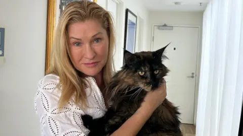 Margo Neas holds her cat Mittens in corridor of her home in Melbourne. Photo: 22 January 2025