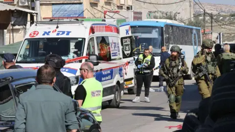 Israeli soldiers and paramedics at the scene of a deadly shooting attack on a bus and other vehicles in the village of al-Funduq, in the occupied West Bank (6 January 2025)