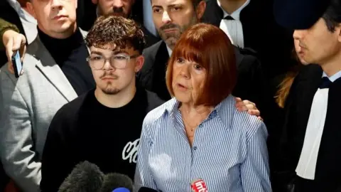 Gisèle Pelicot speaking outside court surrounded by onlookers 