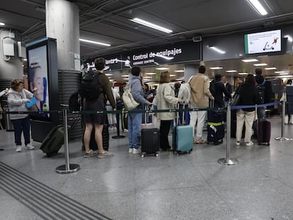 Varias personas esperan para pasar el control de equipajes en la estación de Atocha en Madrid este lunes.