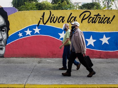 Dos ciudadanos caminan frente a un mural cerca de un colegio electoral, el domingo en Caracas.