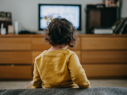 Una niña ve la televisión tradicional en casa.