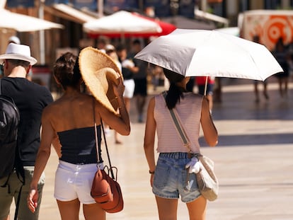 Varios turistas se protegen del calor en plena ola, el 12 de julio, en Málaga.