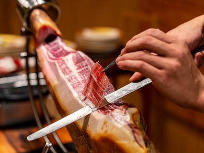 Primer plano de un chef cortando un jamón ibérico.