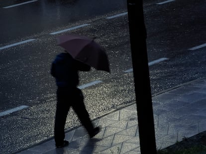 Un hombre se protege del viento y de la lluvia con un paraguas.