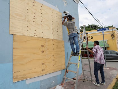 Personas tapian una ventana ante el avance del huracán Milton, en Progreso, México.