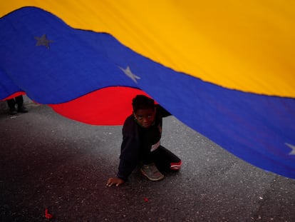 Un niño juega bajo una bandera de Venezuela durante una marcha en Caracas, en febrero de 2022.