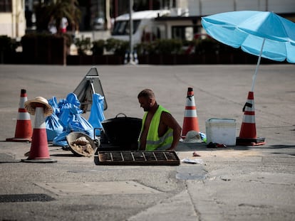 Un trabajador se protege del sol con una sombrilla en Valencia, el jueves.