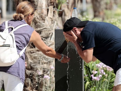 Dos personas se refrescan en una fuente del centro de Valencia.