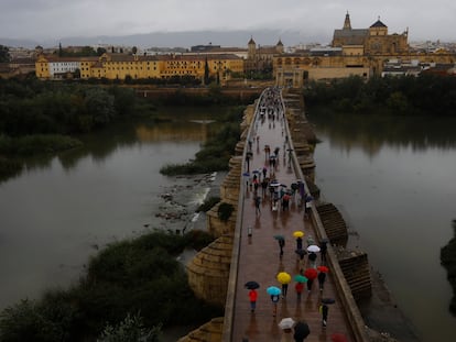 Varias personas se protegen con paraguas de la lluvia mientras pasean por el puente romano de Córdoba, el pasado sábado.