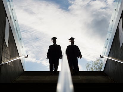 Graduados universitarios con toga y birrete subiendo unas escaleras.