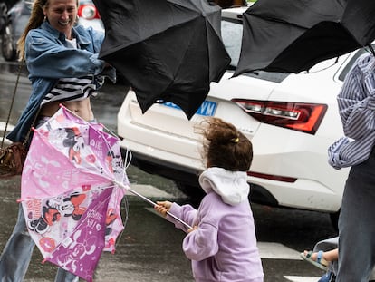 Varias personas tratan de dominar sus paraguas en San Sebastián.