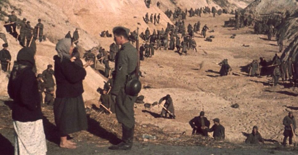 In 1941, Soviet POWs bury victims of the massacre as Ukrainian women talk with Nazi soldier.