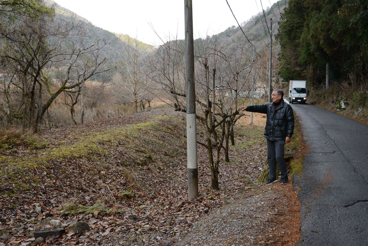 ３工区の廃線敷を指し示す竹井会長。右が県道宇津可部線