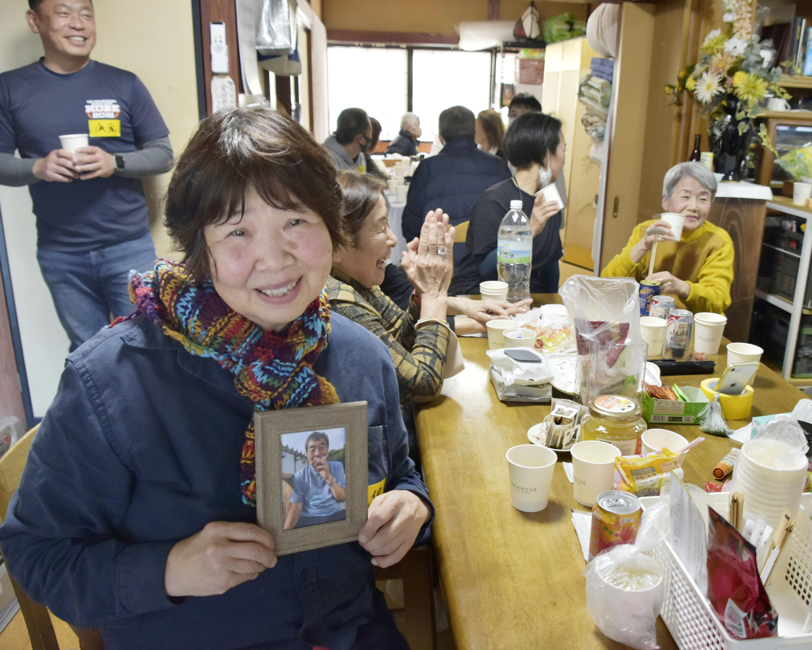 しのぶ会で、山根敏博さんの遺影を手にする妻けい子さん＝19日、石川県輪島市