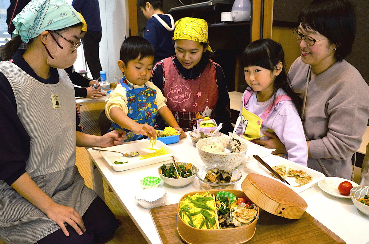 高校生に教わりながら弁当を盛り付ける親子ら（田野町の遊分舎）