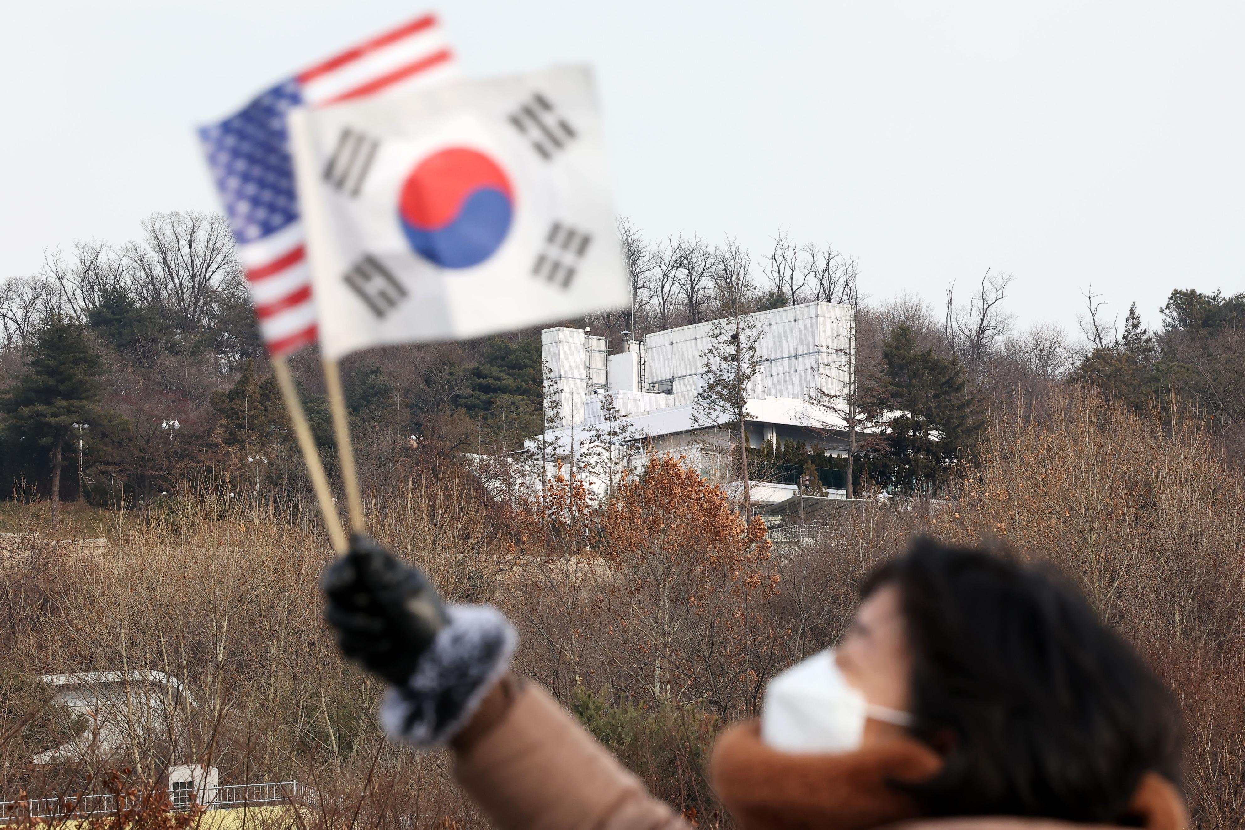 8日、韓国の尹錫悦大統領の公邸（奥）近くで国旗を振る尹氏支持者＝ソウル（聯合＝共同）