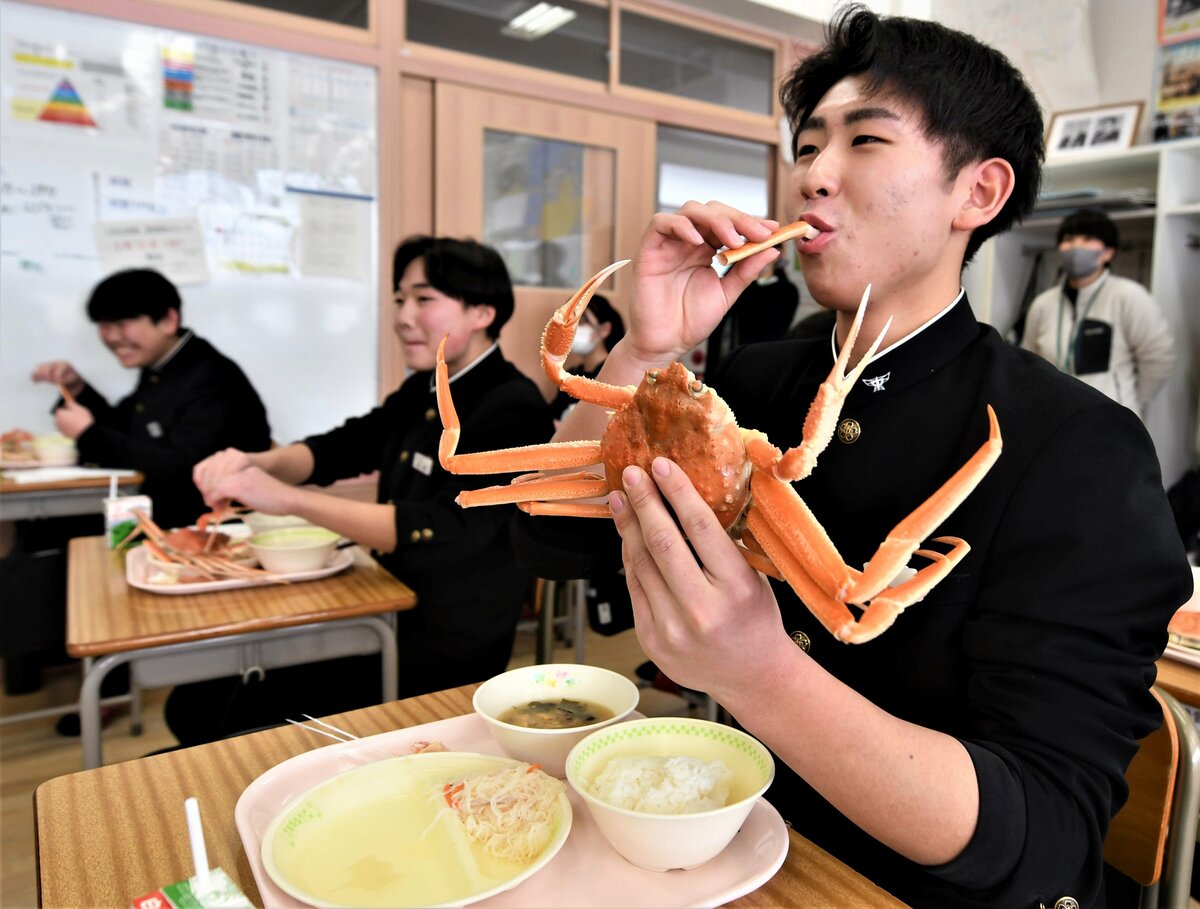 若松葉ガニを食べながら満足そうな表情を浮かべる生徒＝７日、岩美町浦富の岩美中