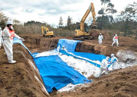 殺処分した鶏や汚染物品を詰めた袋を埋却する鹿児島県職員ら＝８日、霧島市（県提供）