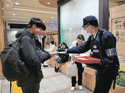 駅の利用客に啓発チラシを手渡す警察官