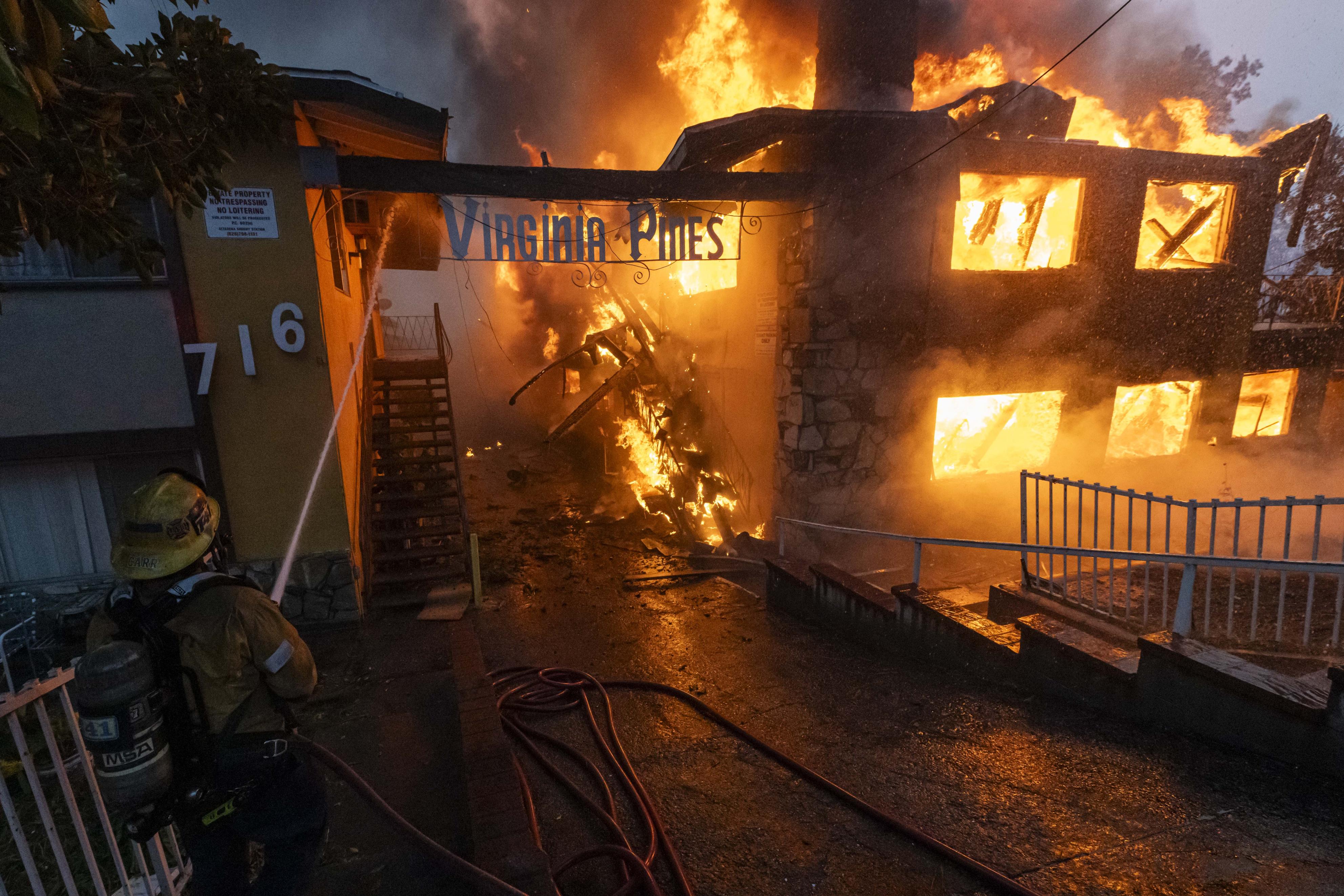 山火事で炎上する住宅に向けて放水する消防士＝8日、米カリフォルニア州アルタデナ（ゲッティ＝共同）