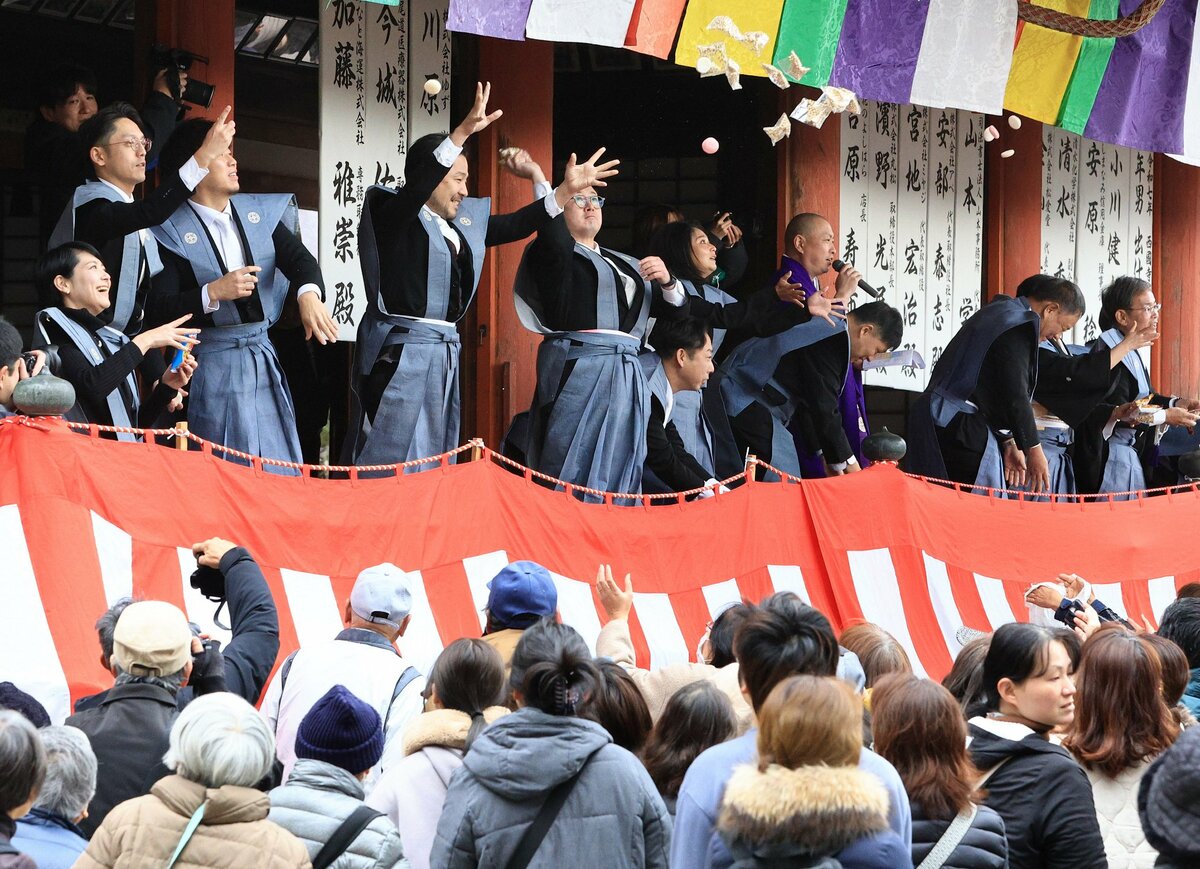 参拝客に向けて勢いよく豆や餅をまく年男と年女たち（撮影・大川万優）