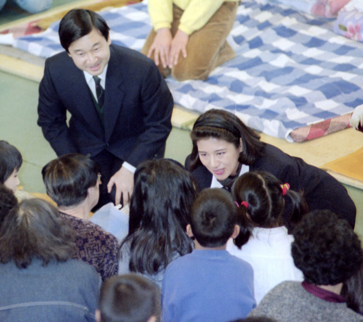 避難所の小学校で、身を乗り出して励まされる天皇、皇后両陛下＝1995年2月、神戸市中央区の諏訪山小学校