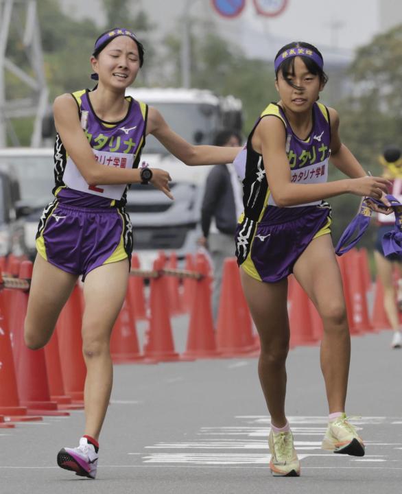 【高校女子】聖カタリナ学園の２区井門（左）からたすきを受け取りスタートする３区宮脇＝香川県坂出市