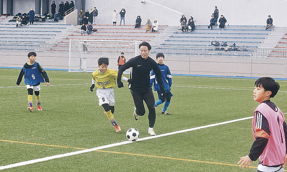 駒沢選手（中央）と一緒にプレーする子どもたち＝白山市松任総合運動公園