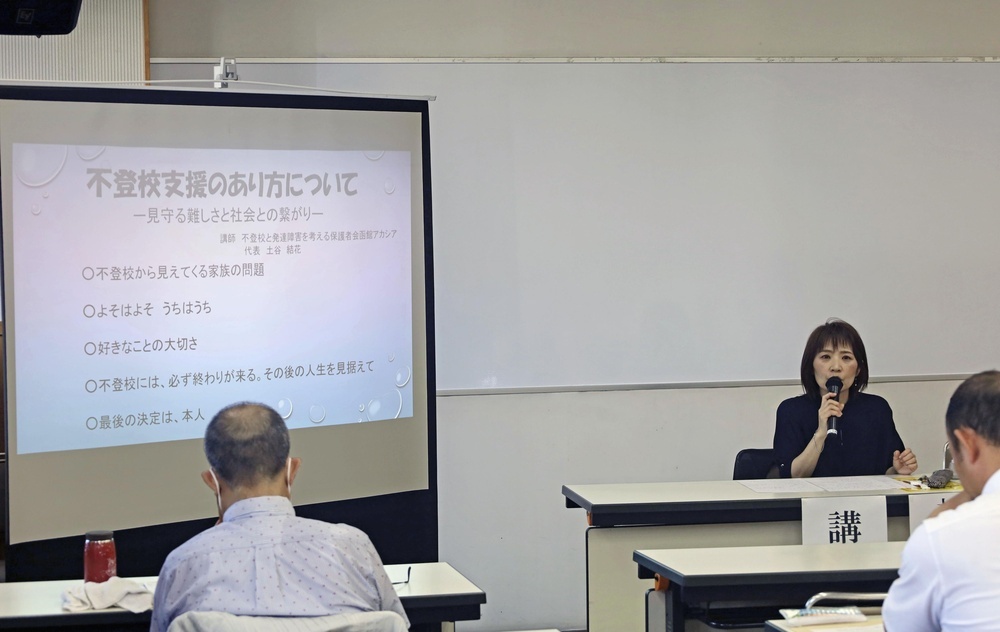 不登校について講演する「函館アカシヤ」代表の土谷結花さん（右奥）＝2024年8月、北海道函館市