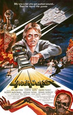 A film poster with a young man with a laser gun extended from his arm, shooting out the title "Laserblast". A tagline at the top reads "Billy was a kid who got pushed around... Then he found the power". The top left shows two extraterrestrial aliens on top of a burning building, opposite an extraterrestrial spacecraft. Below the burning building, people are seen running away on the street. Credits for the film appear below the title, and a skeleton on fire is at the bottom of the image.