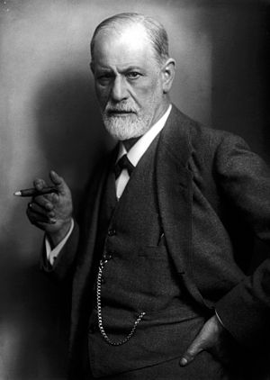 photograph of a balding man with a beard; holding a cigar and wearing a suit