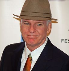 A man wearing a suit, a multi-colored tie, and a tan hat.