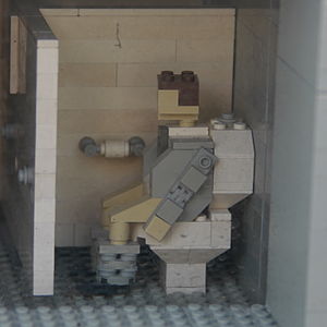 A Lego man using the toilet at Grand Central Station