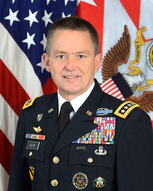 A man in a military uniform in front of flags