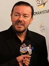 A man in a black suit with a Comedy Central microphone held in front of him.