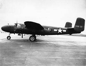 Black and white photo of an early bomber parked perpendicular to camera, facing left. Rearward of the wing is a star in front of horizontal stripes.