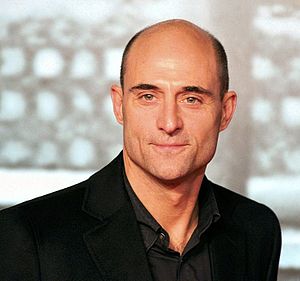 A head-and-shoulders view of a bald middle-aged Strong, wearing a dark shirt and black jacket.