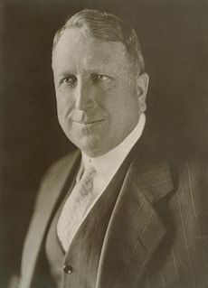 A black-and-white photograph of a middle-aged man in a business suit.