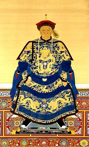 Full-face painted portrait of a severe-looking sitting man wearing a black-and-red round cap adorned with a peacock feather and dressed in dark blue robes decorated with four-clawed golden dragons.