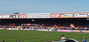 One of the stands of the Bootham Crescent association football ground, with supporters waving flags and a grass field below