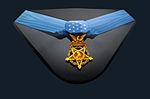 U.S. Army Medal of Honor displayed with a light blue neck ribbon with a gold star shaped medallion hanging from it. The ribbon is similar in shape to a bowtie with 13 white stars in the center of the ribbon.