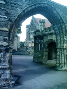 A school viewed through a stone gateway